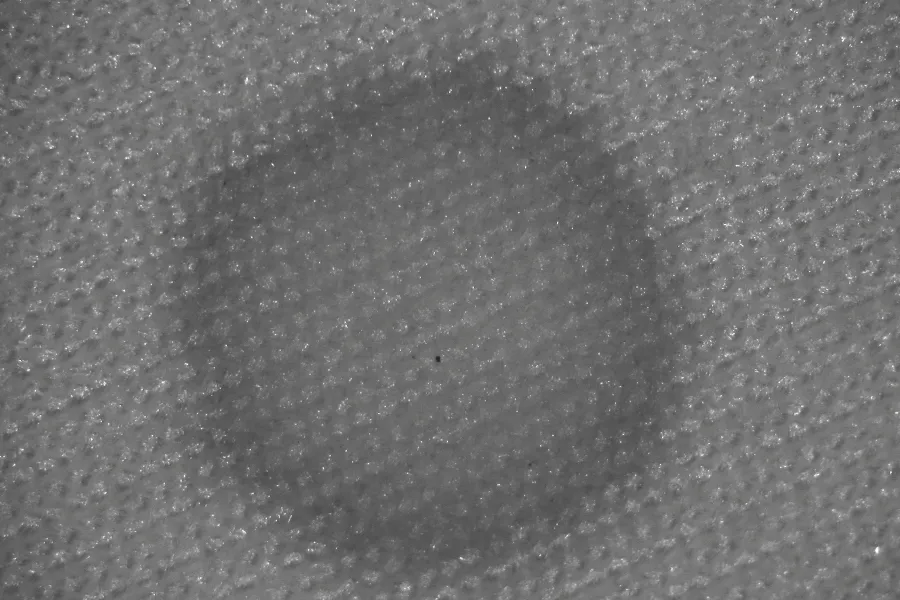 Magnified forensic view of a blood stain detected across the textured fibres of a fabric surface.